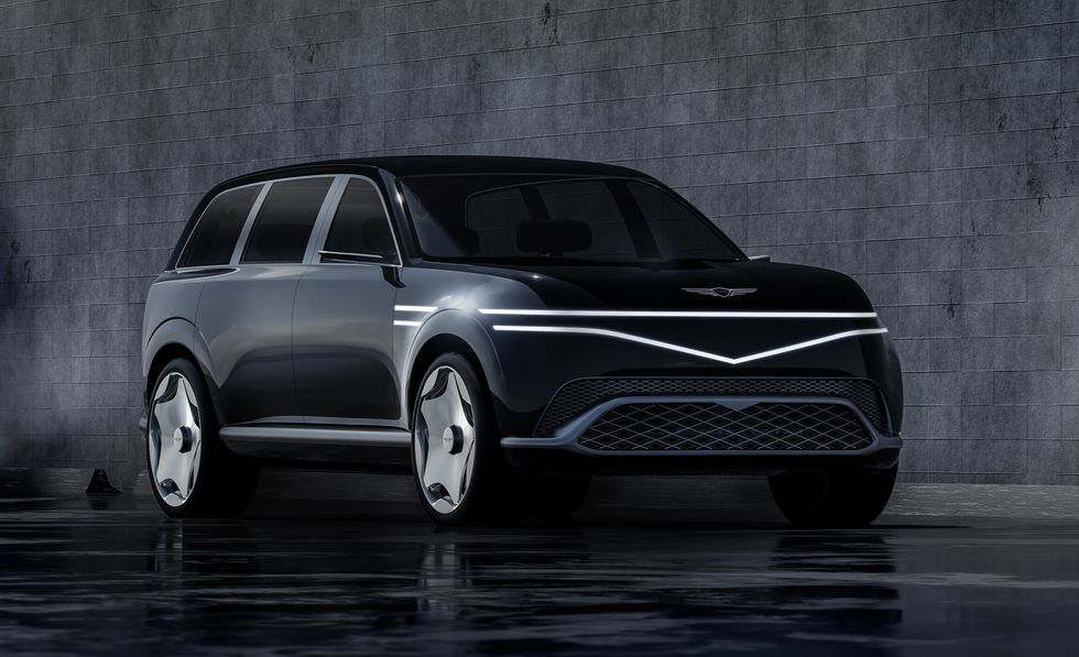 Sleek silver concept SUV on a dark reflective floor against a textured gray wall.