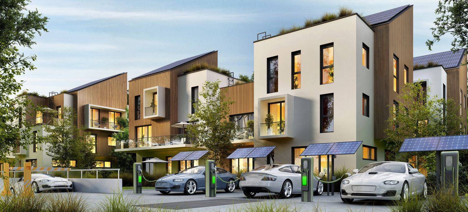 Modern townhouse complex with cars parked outside and landscaped greenery at dusk
