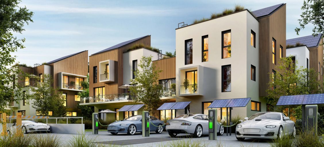 Modern townhouse complex with parked cars, balconies, and landscaped greenery at dusk