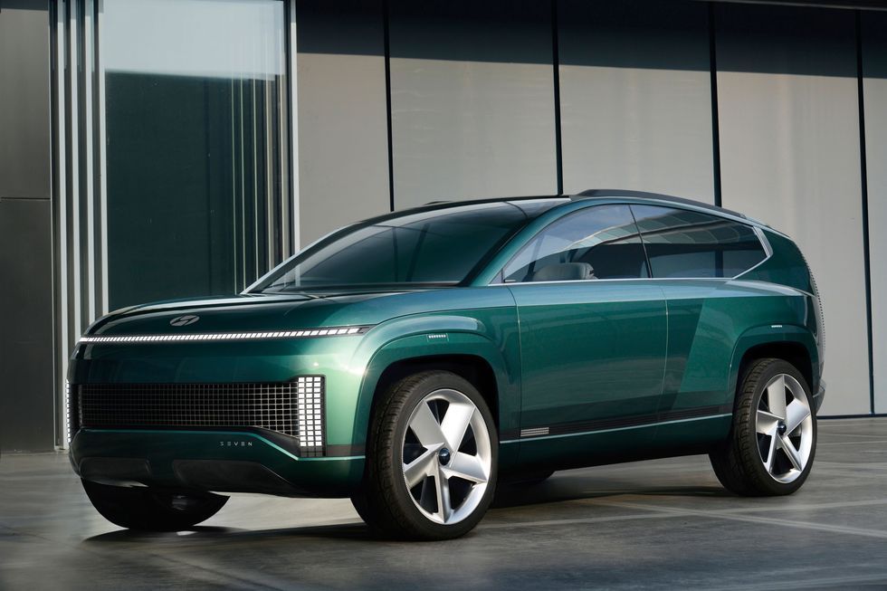Green futuristic SUV concept car parked indoors with a sleek metallic finish and large wheels