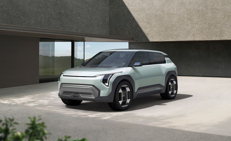 Silver concept SUV parked outside a modern building with a glass wall and covered entryway