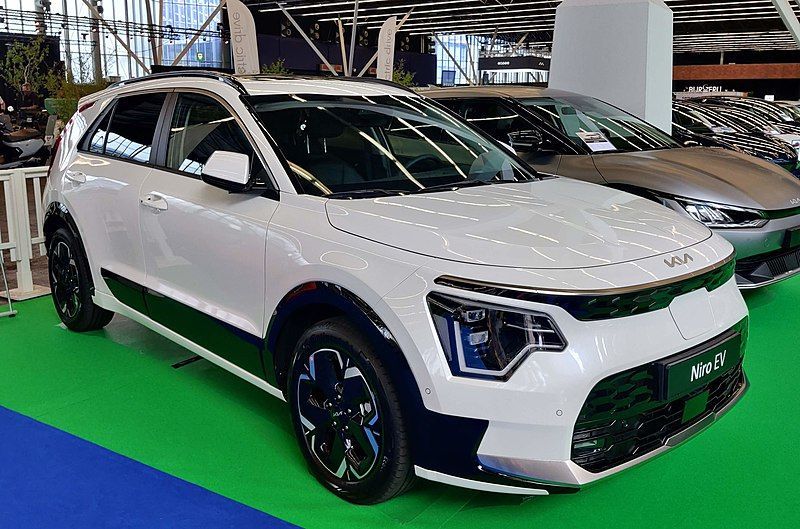 White SUV displayed indoors on a green platform at an auto show