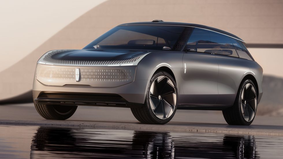 Futuristic silver concept car on a reflective surface at sunset