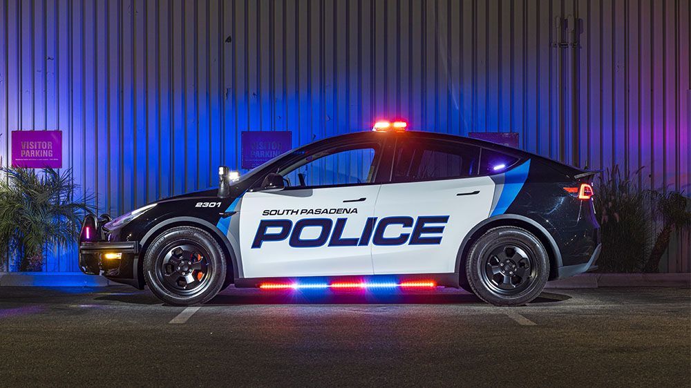 Police car parked at night with flashing red and blue lights beside a building