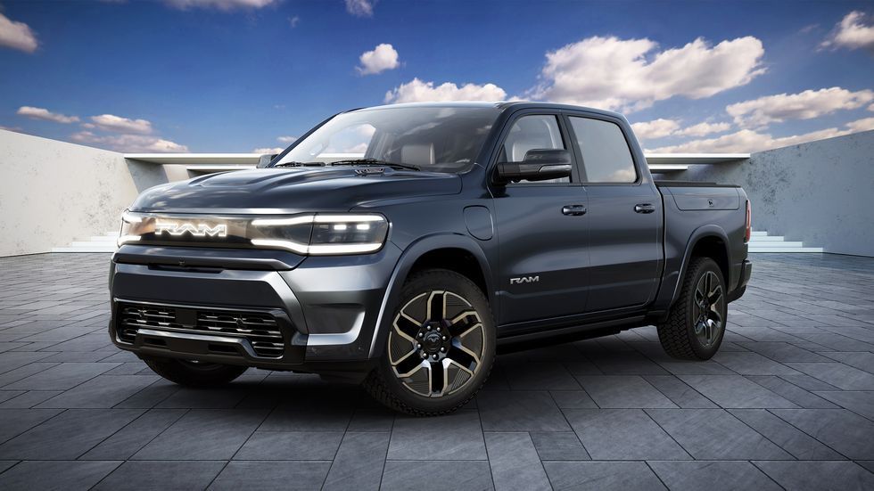 Dark gray pickup truck parked on a paved lot under a blue sky with clouds