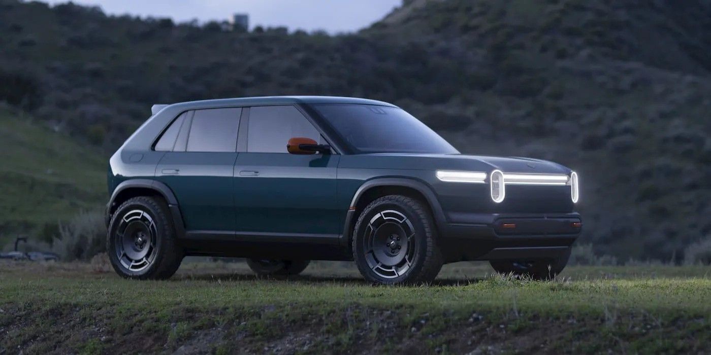 Dark green compact SUV on a grassy field with mountains in the background
