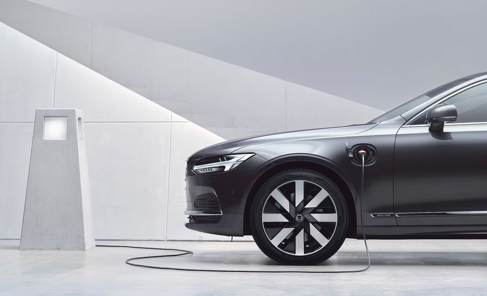 Black electric sedan charging at a modern station in a minimalist white garage