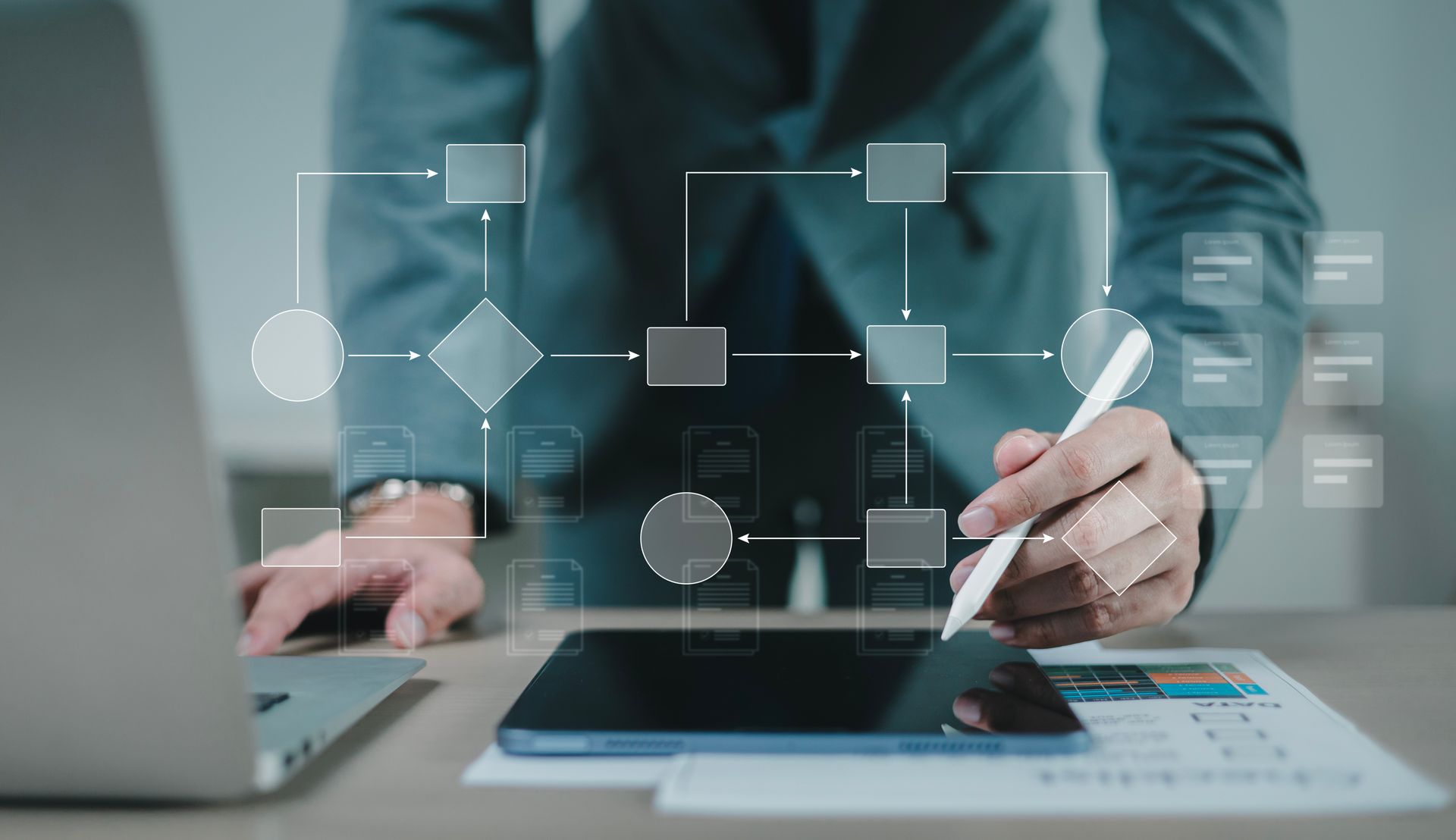 Man at a desk with tablet and laptop with a infographic in the foreground.