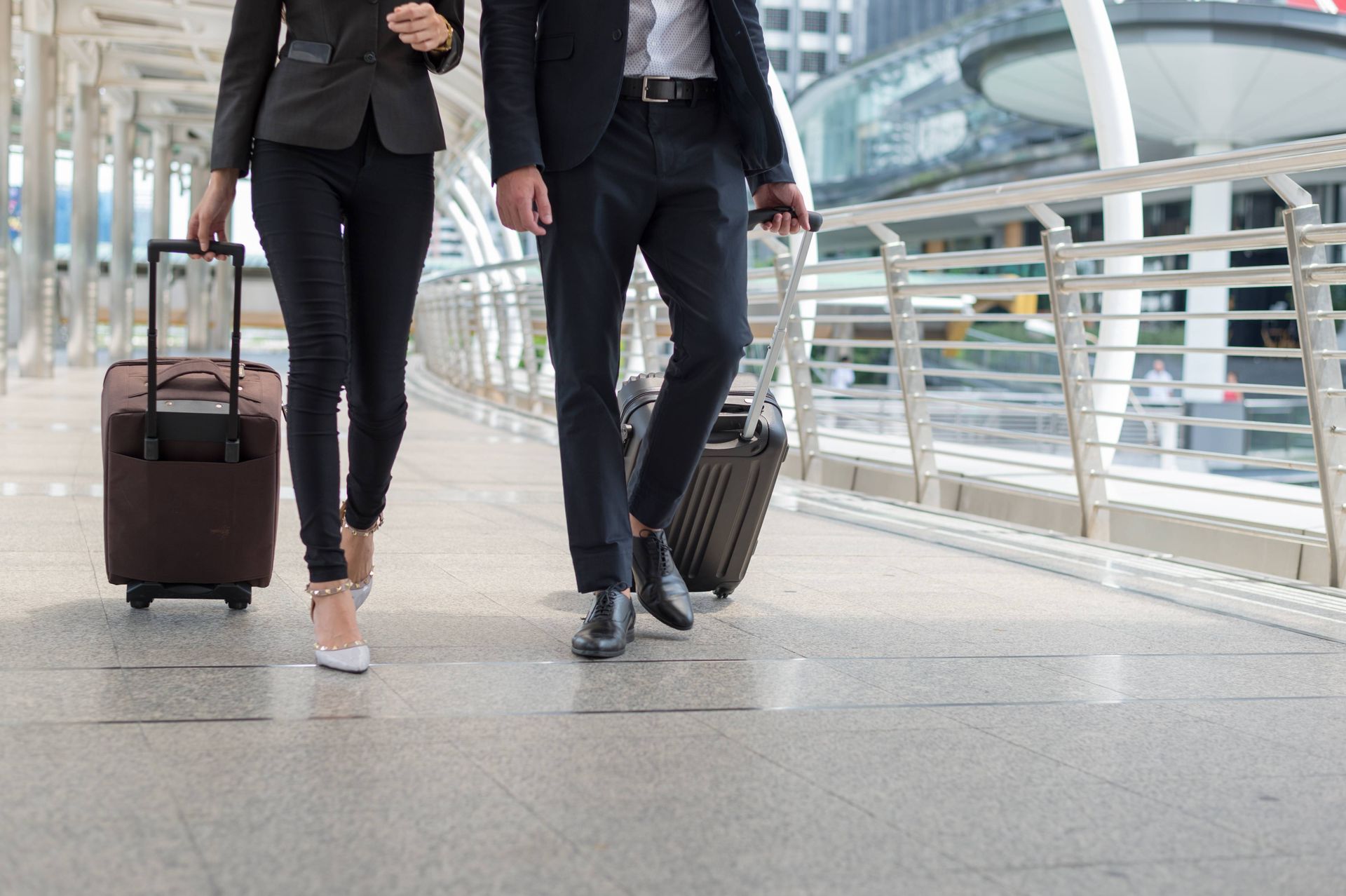 Man and woman wheeling luggage through airport.