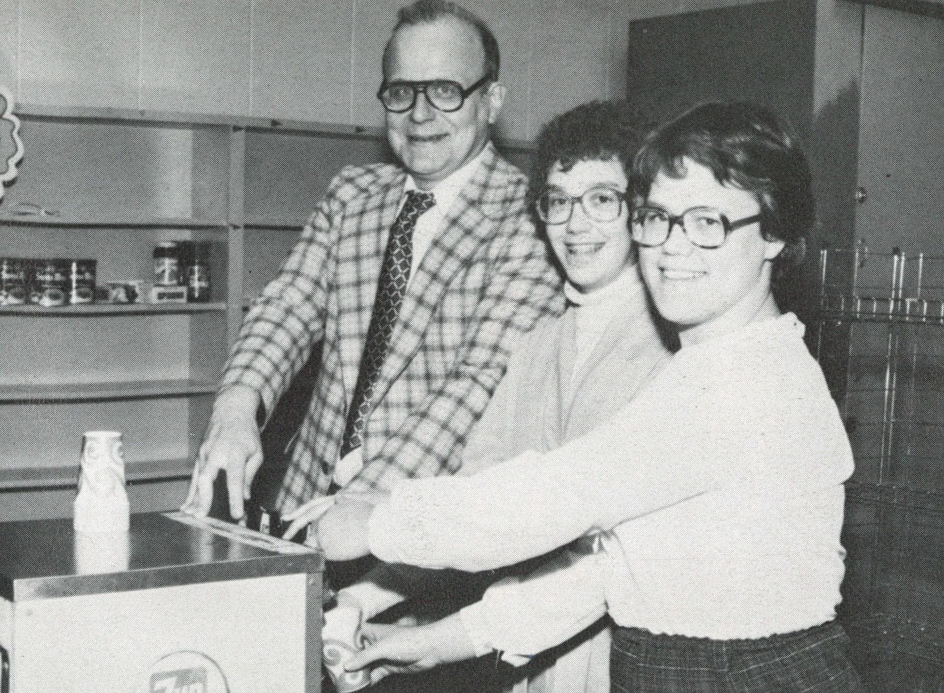 Two women and one man in the canteen, looking at the camera and smiling