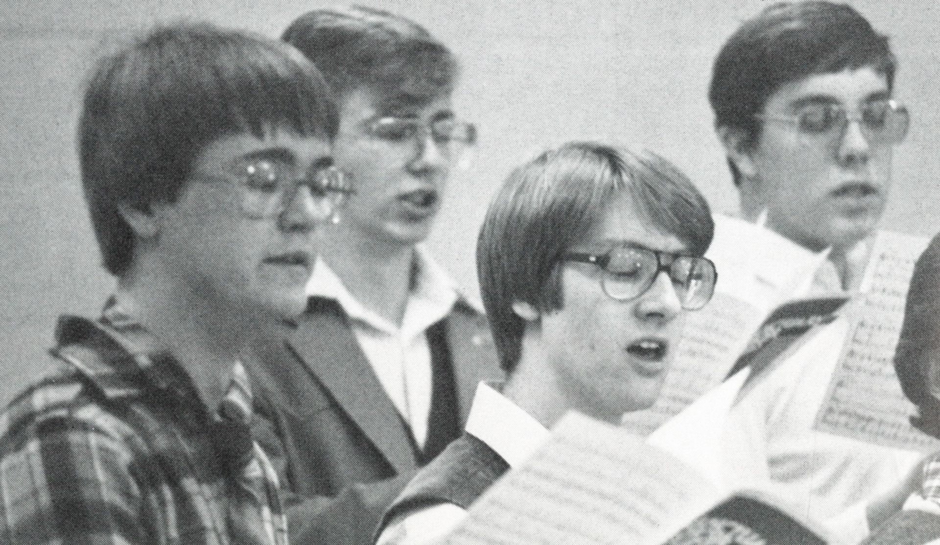 Male students holding music and singing