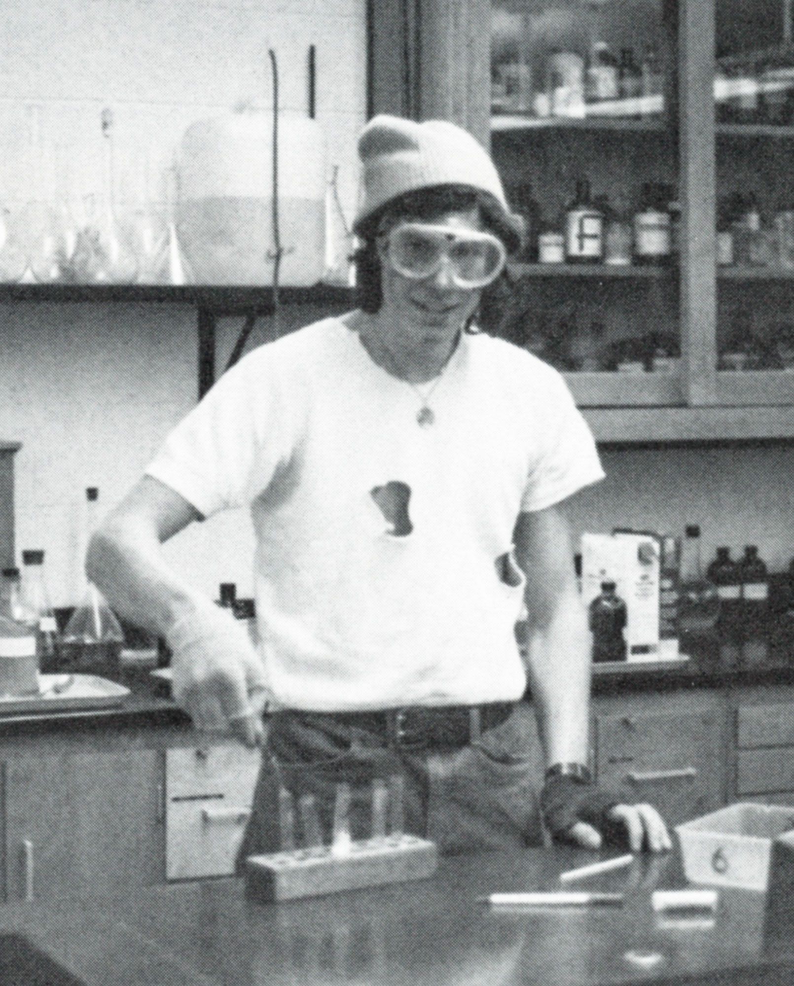 Male student wearing a knitted hat is conducting an experiment in a science lab (he is smiling at the camera)