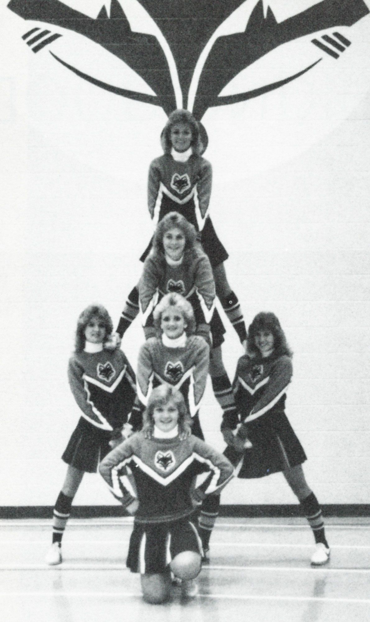 6 cheerleaders in the gym, having balanced themselves into a tower