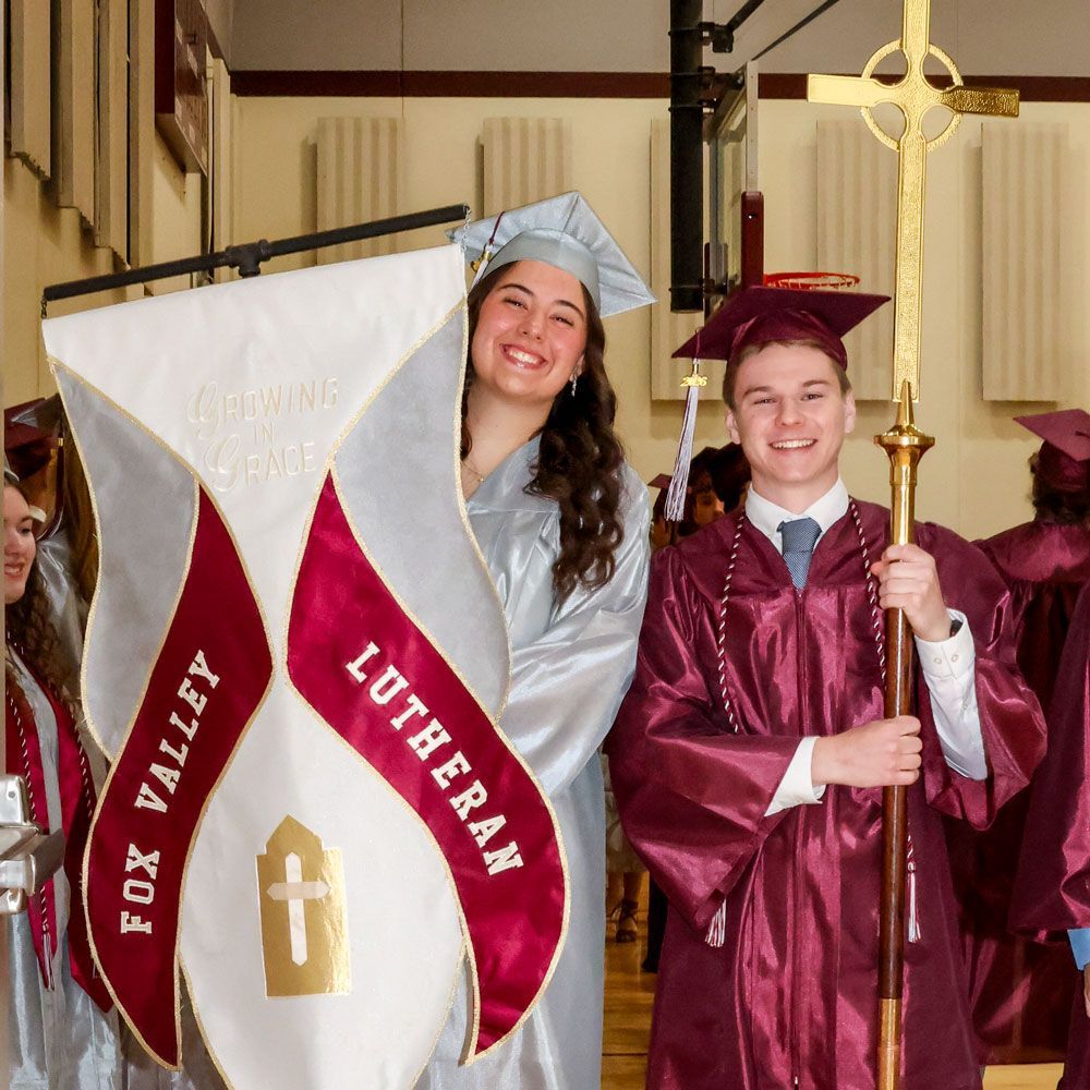 Smiling female student holding FVL banner, smiling male student holding cross, prior to service