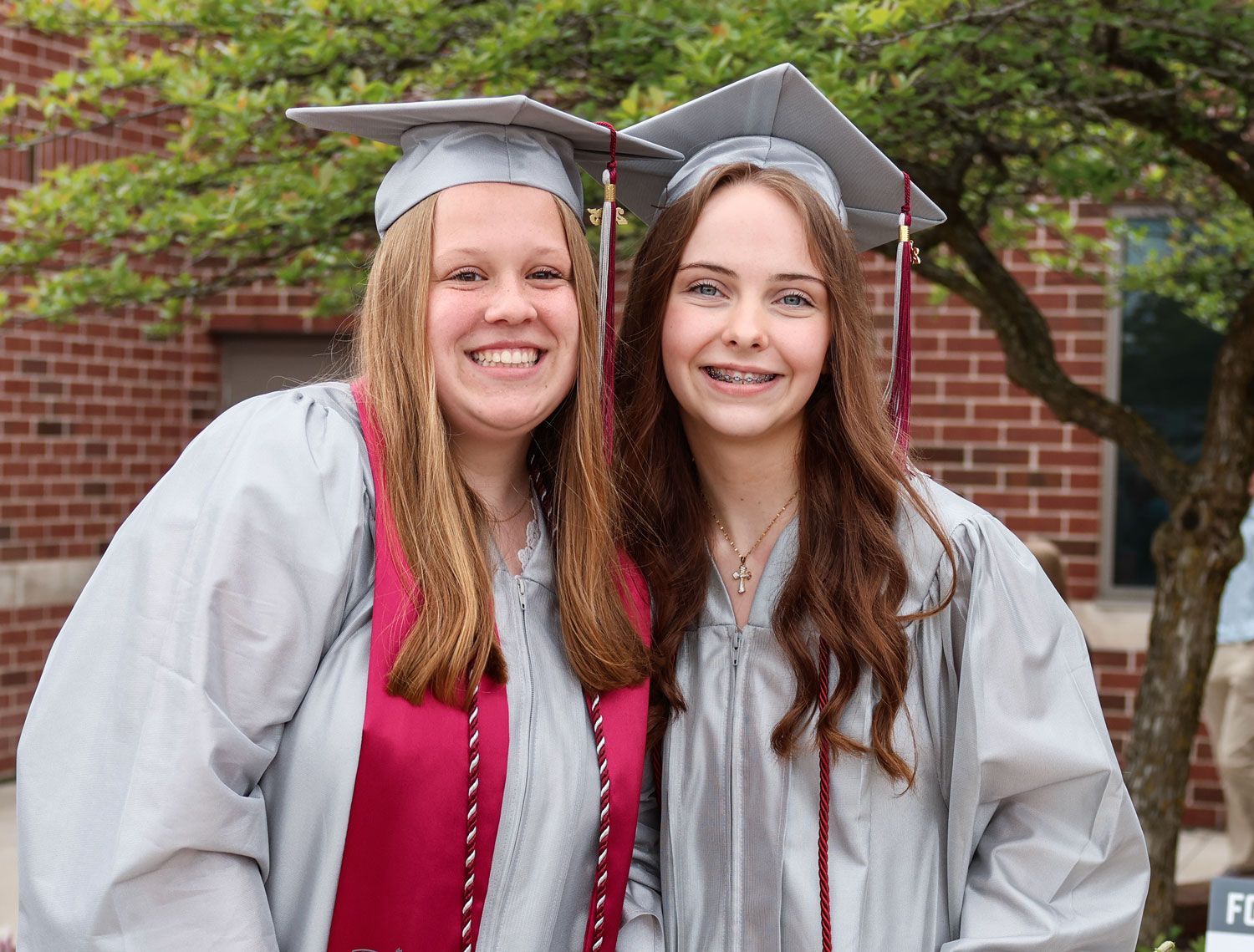 Two smiling girls outside, after graduation service