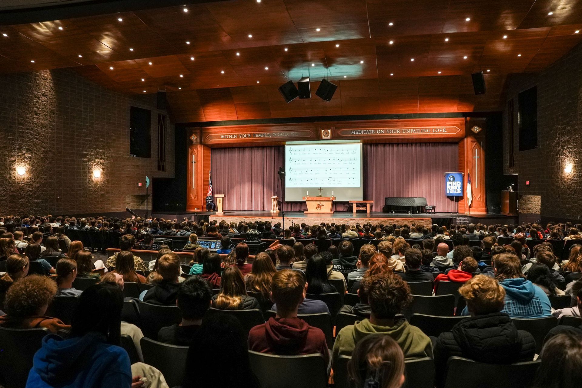 View of the chapel stage from the back of the auditorium, with seats filled