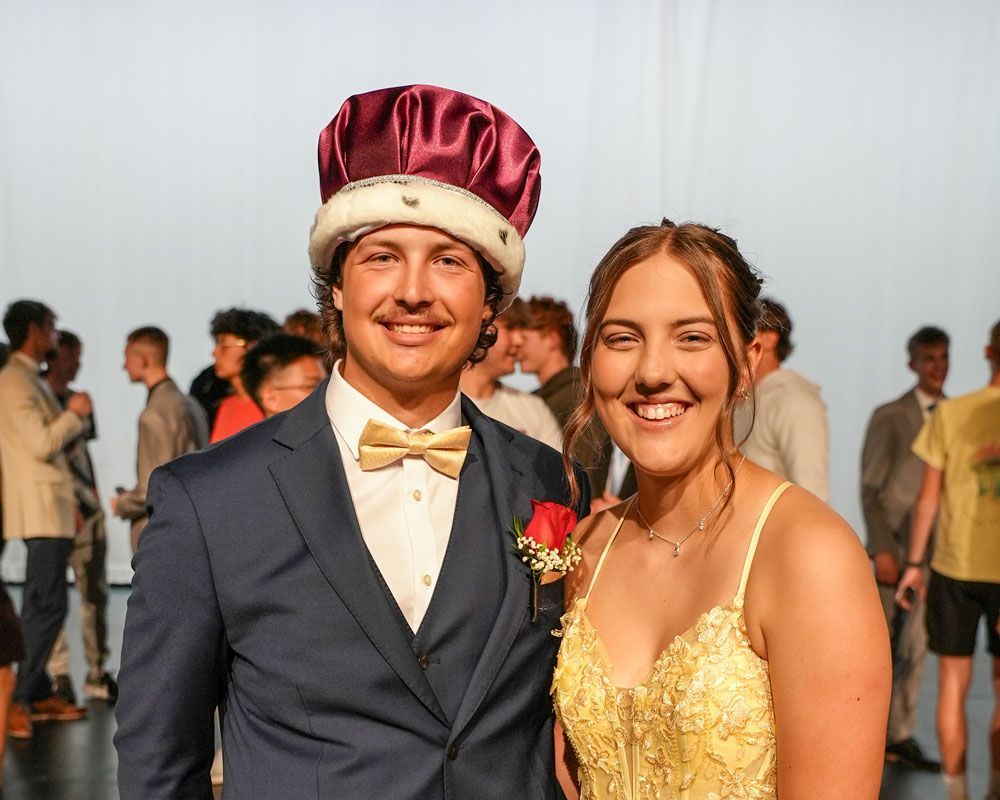 Smiling prom king (wearing his crown) and queen