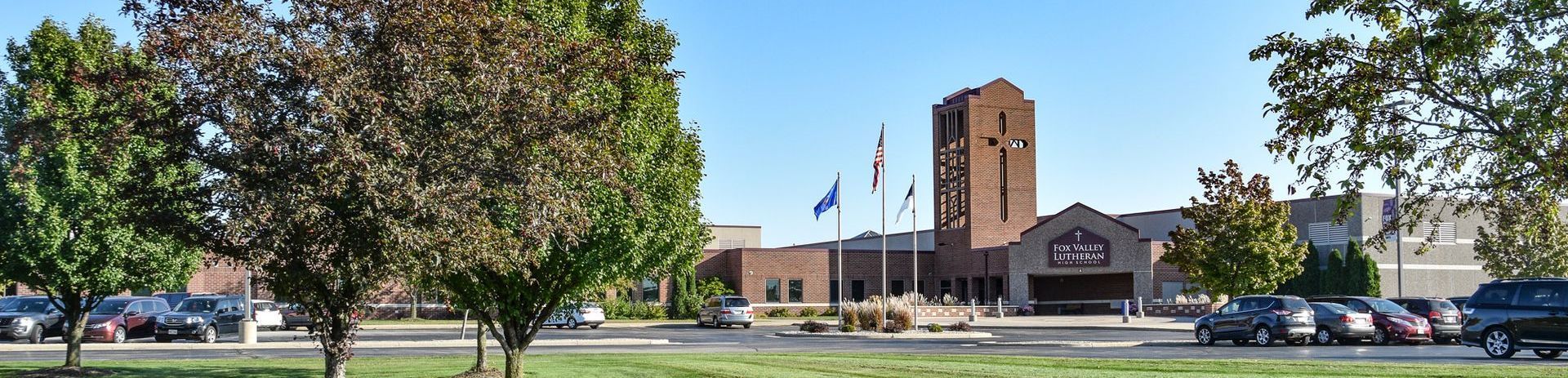 Tower entrance of the school with trees and the parking lot in the foreground