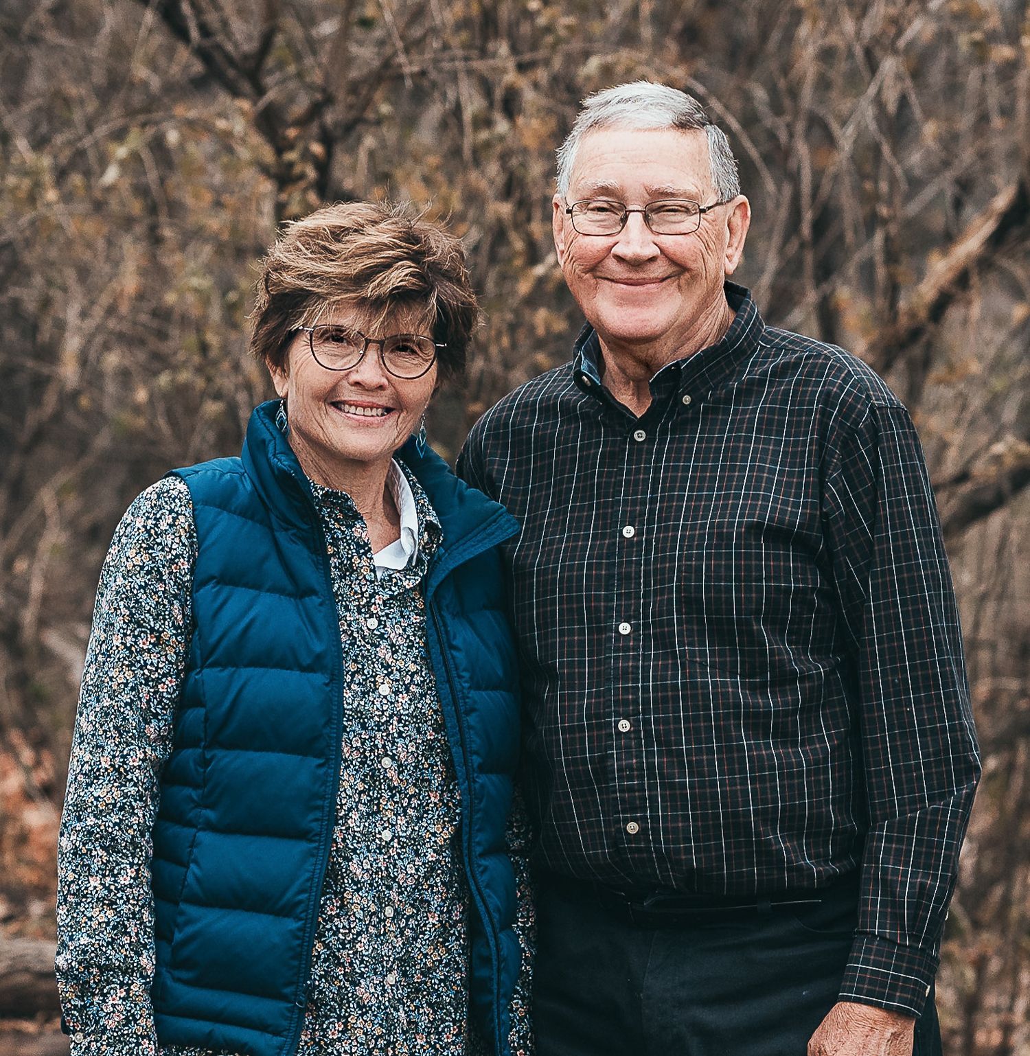 Gloria and Jim Knoll, outside with de-leafed trees in the background