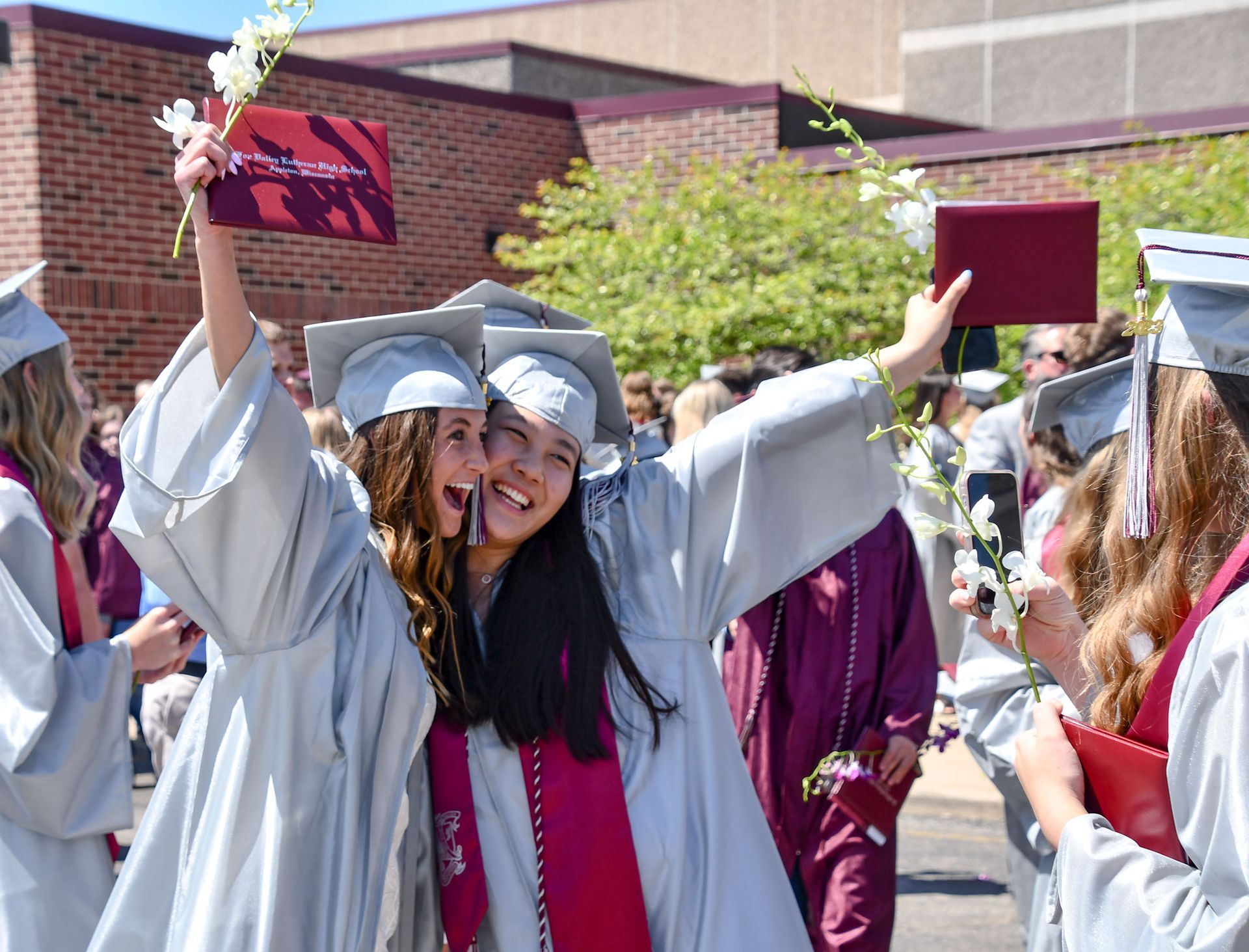 Two happy senior girls, outside the Commons entrance, after graduation. 