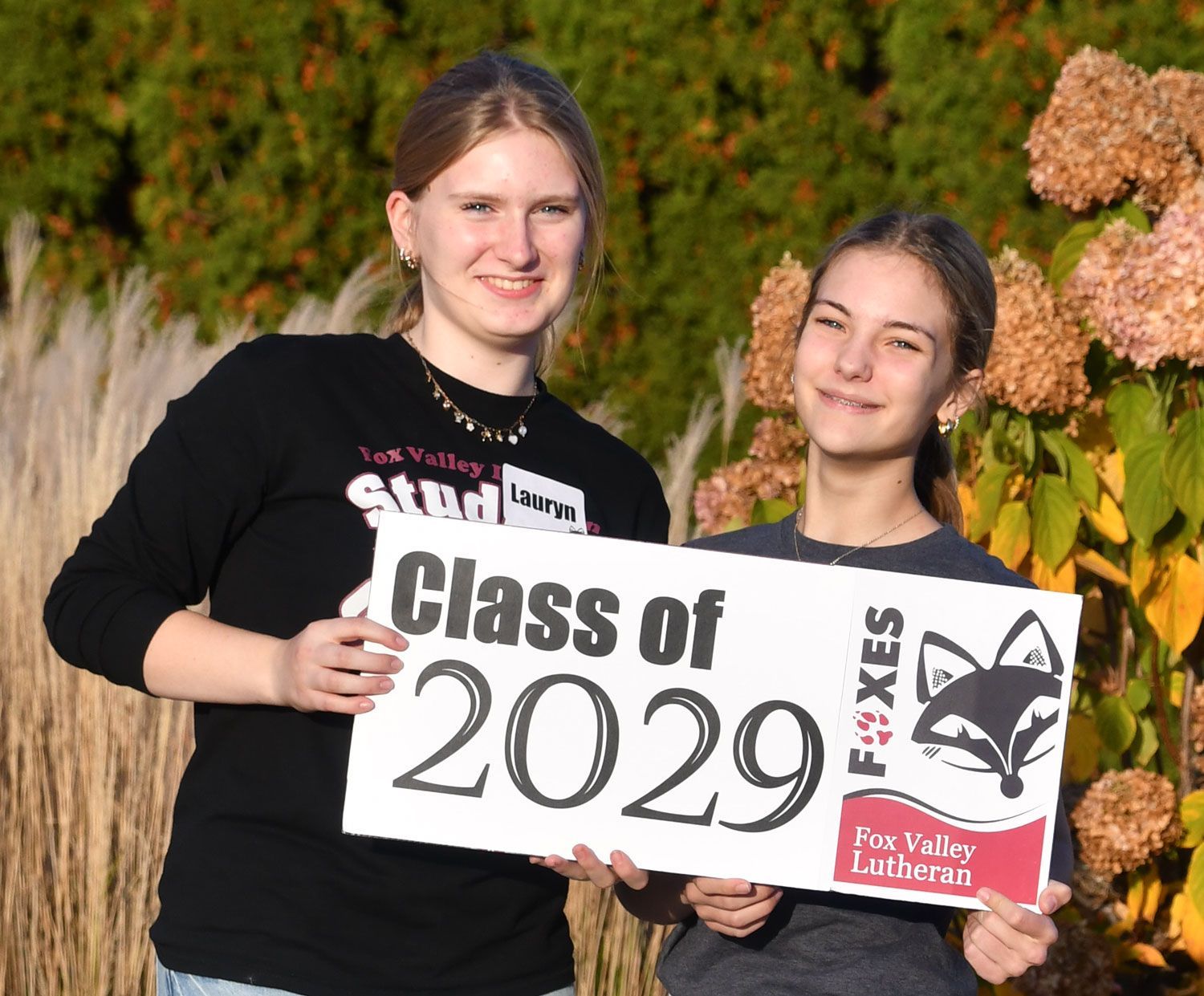 Two smiling girls holding sign that reads 