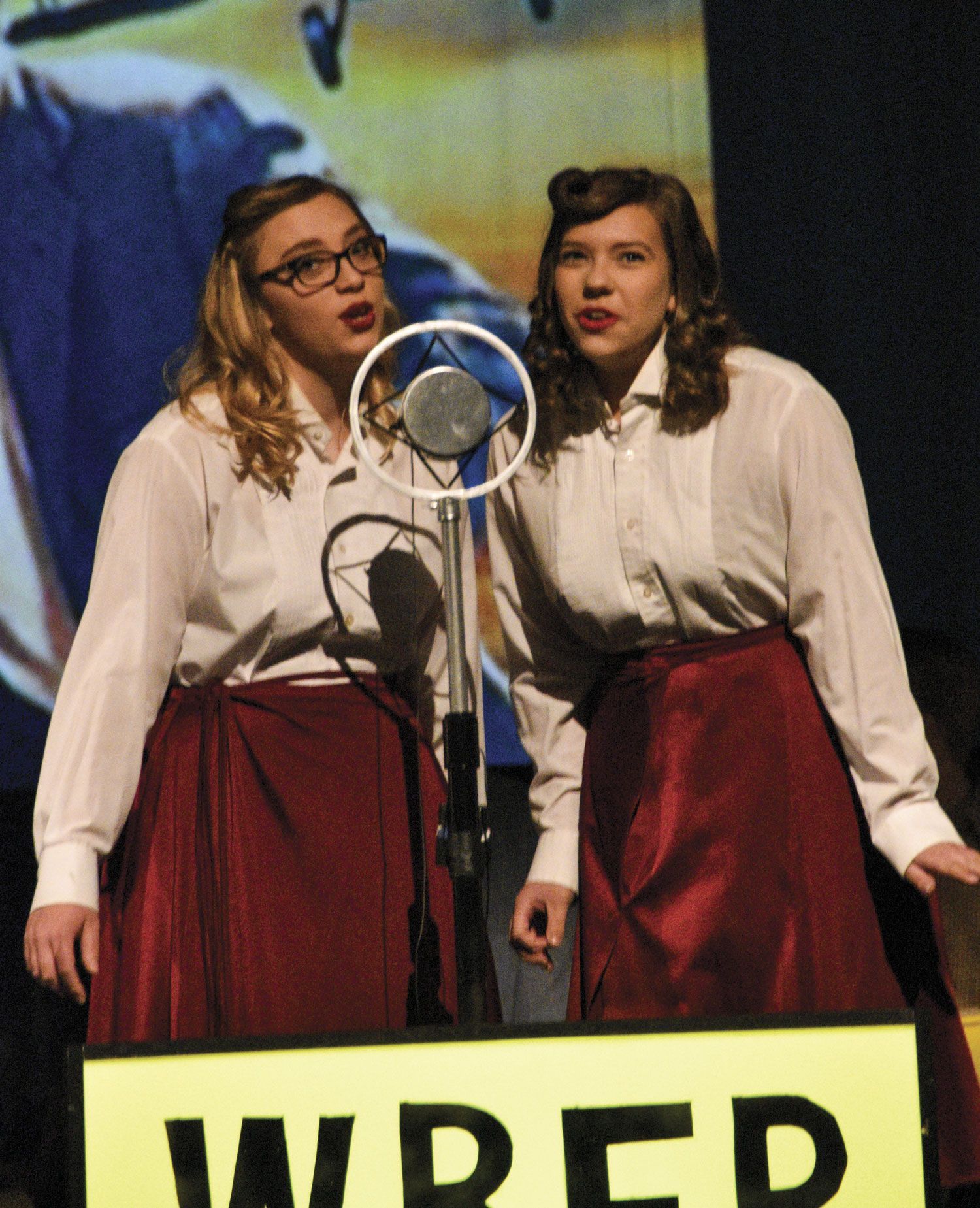Two female students singing at a vintage microphone
