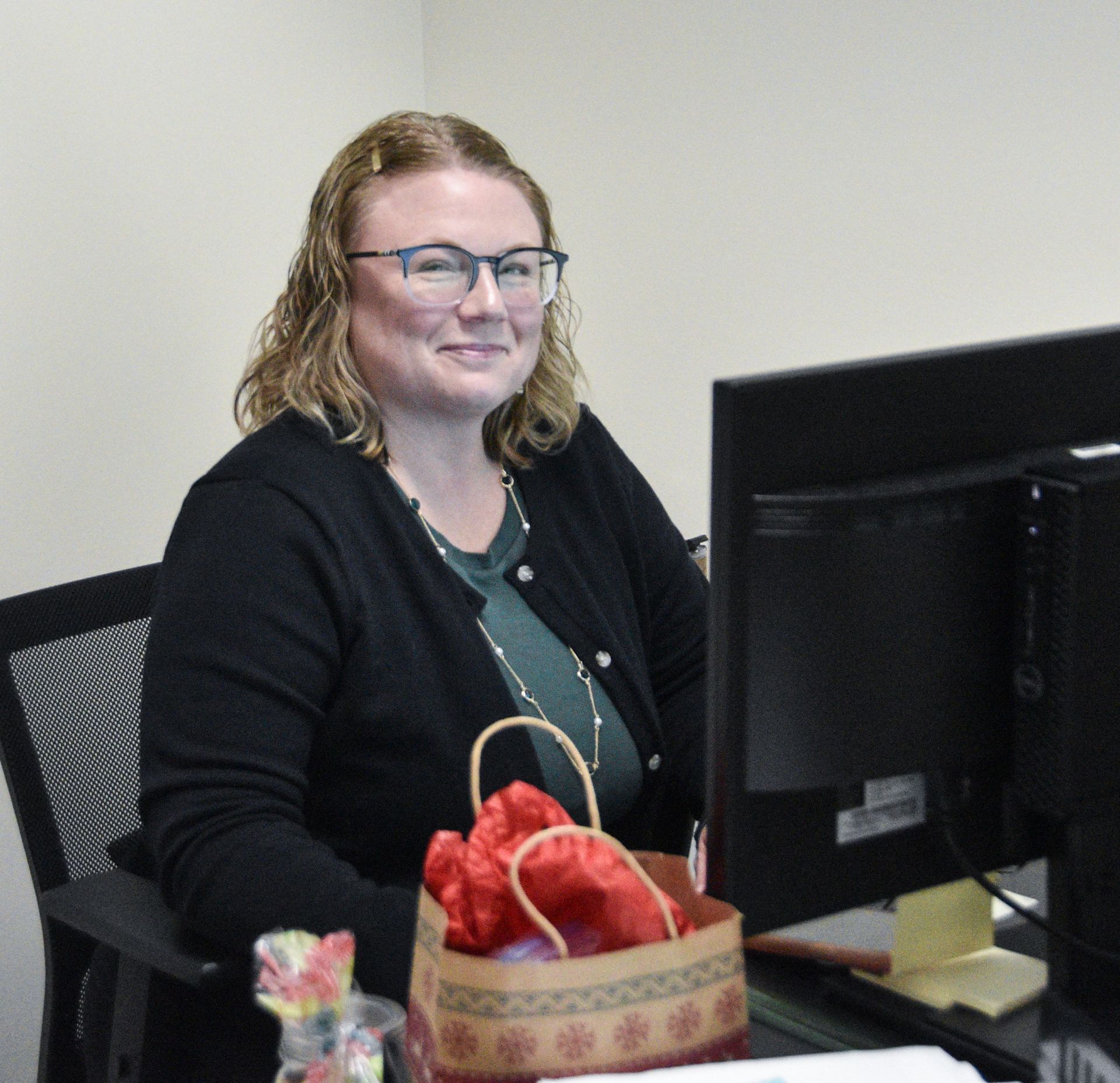 Smiling Mary Block, sitting at her desk