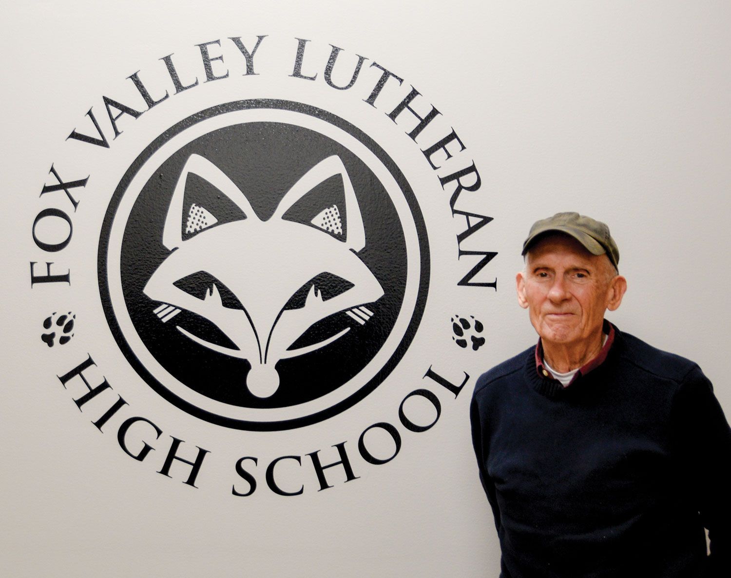 Jerold Huth standing by the FVL foxhead on the wall in a conference room