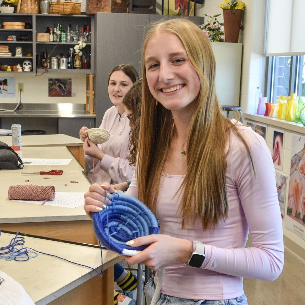 Female student in art class with a yarn basket she is making