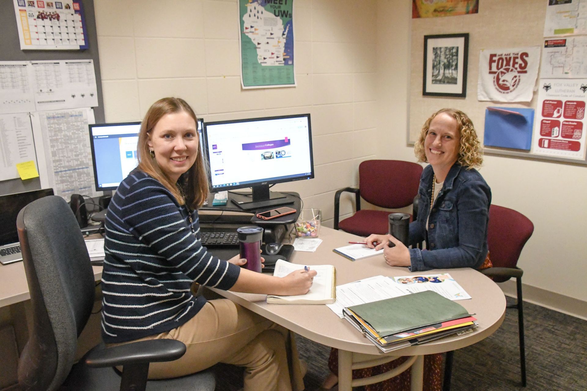 Aleay Friemark sitting at her desk with Heidi Wendland on the other side of the desk.