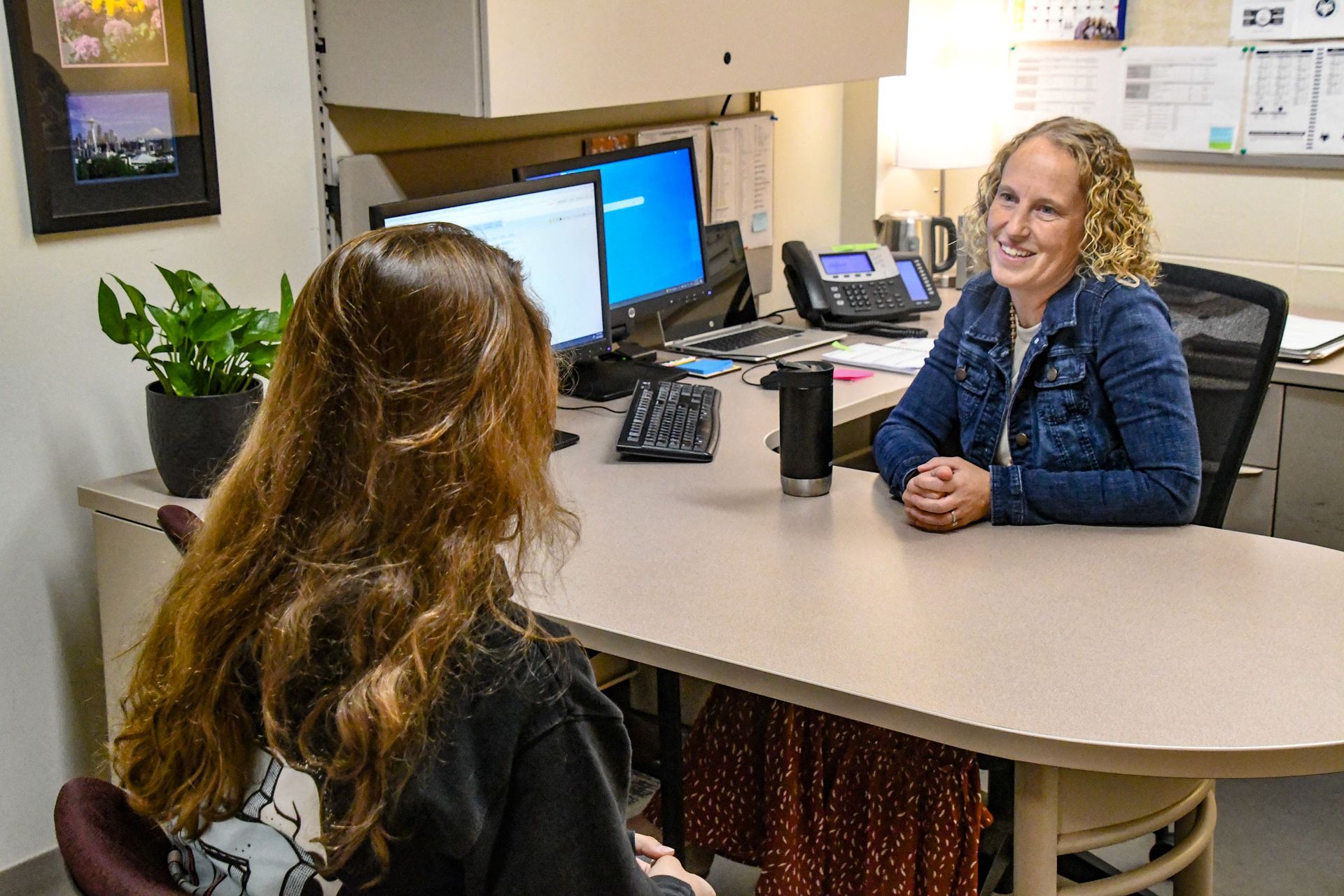 Heidi Wendland sitting at her desk, talking to a student