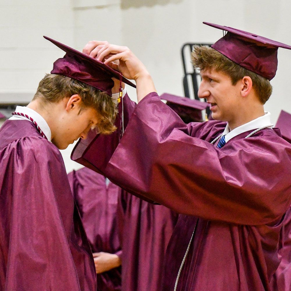 Male student putting mortarboard on a male student's head