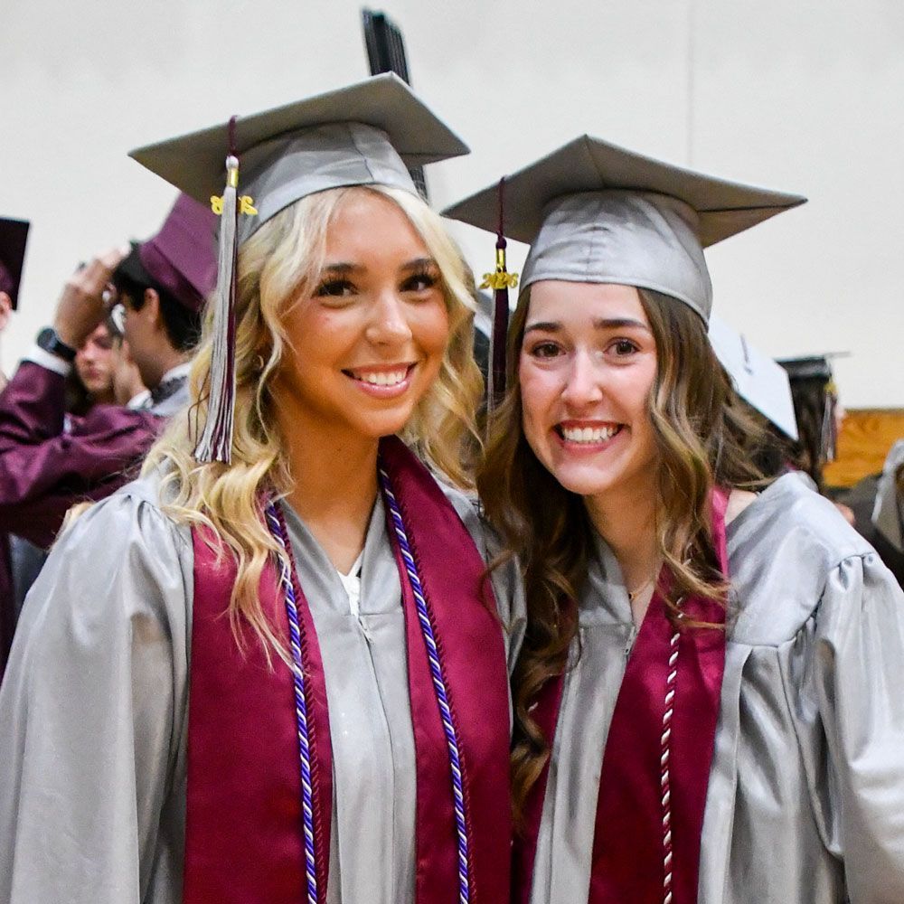 Two smiling female students looking at the camera, and in small gym prior to service
