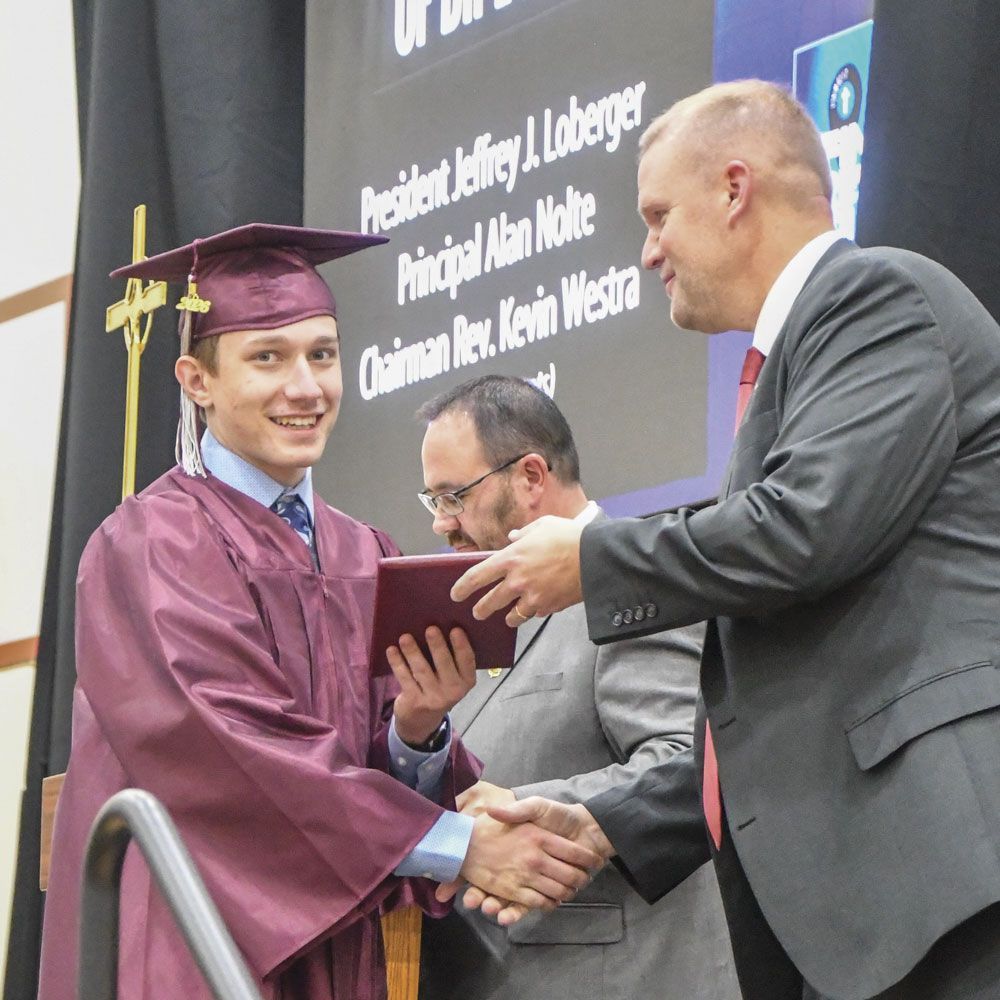 Male student receiving diploma from President Loberger
