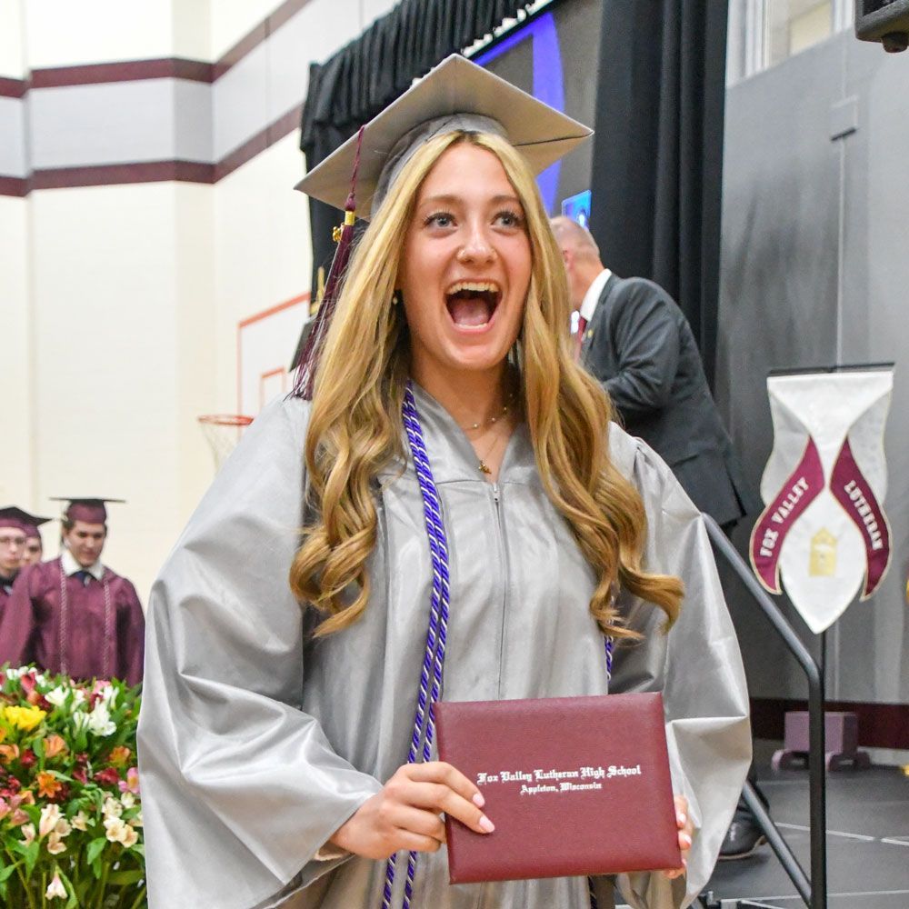 Happy female student displaying her diploma as she walks off the stage