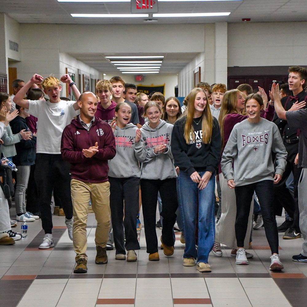 Many students and a coach happily walking down the hallway together