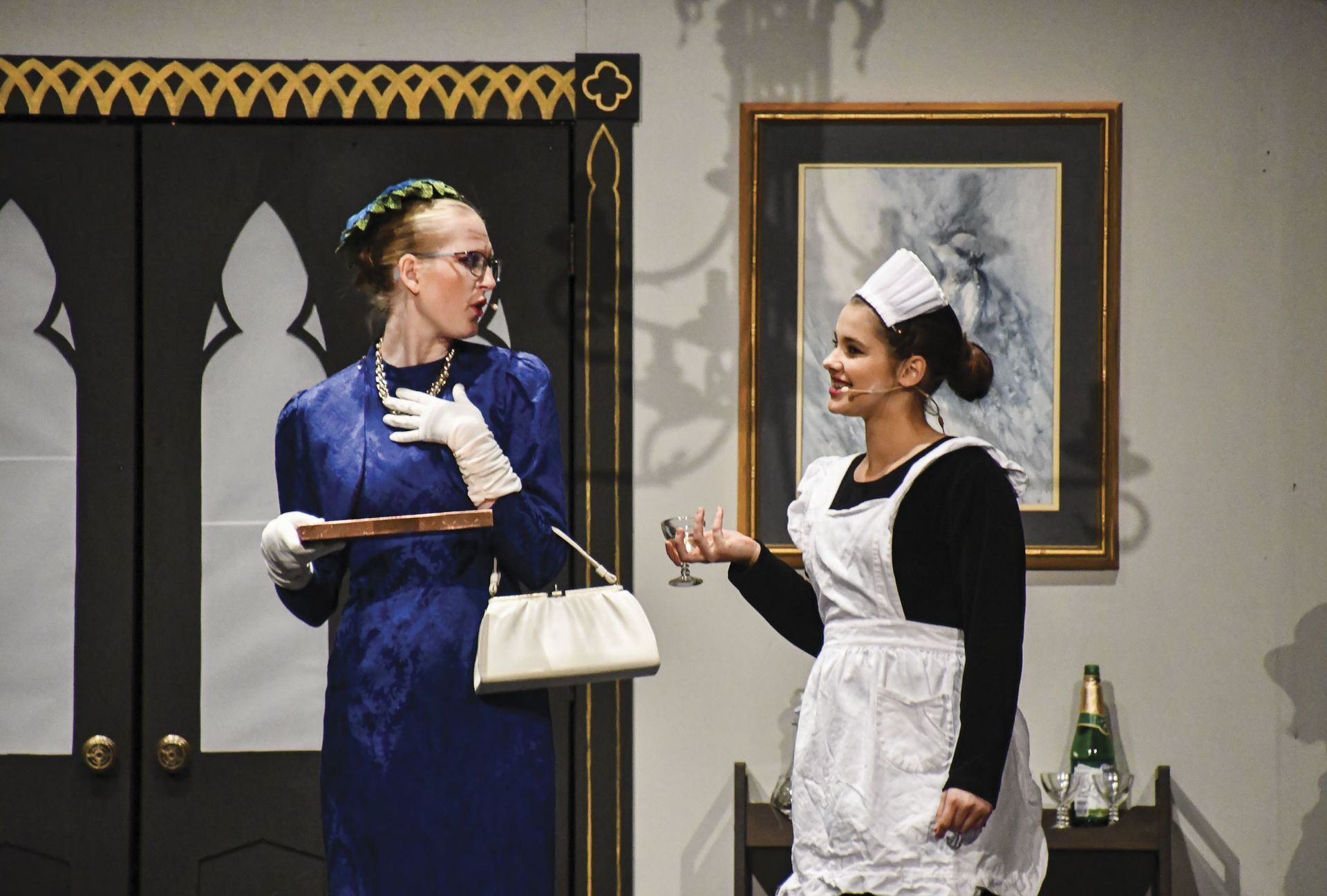 Female with purse and wearing pearls and a second female in a maid's costume