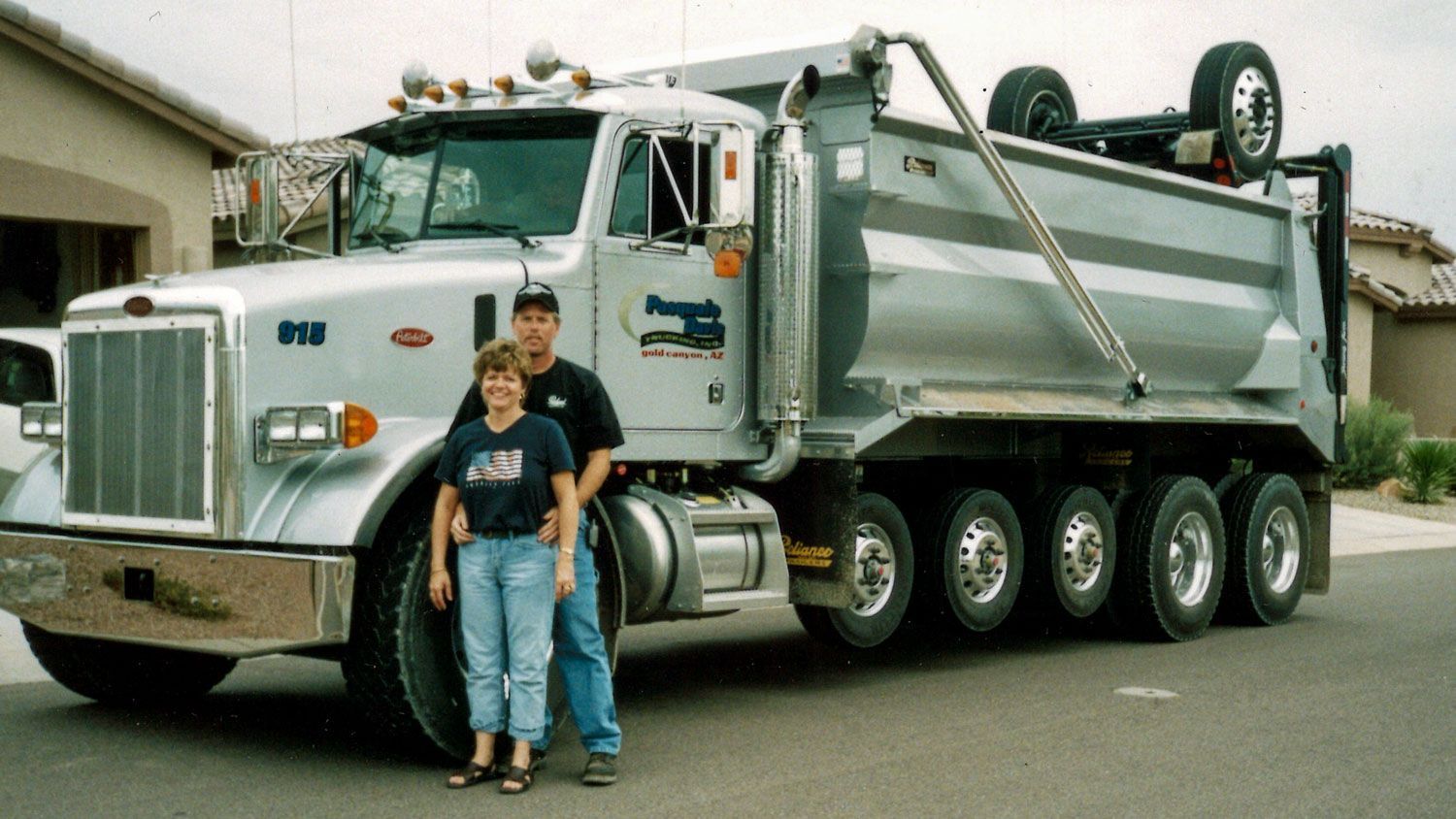 Krista and her husband standing in front of a dump truck