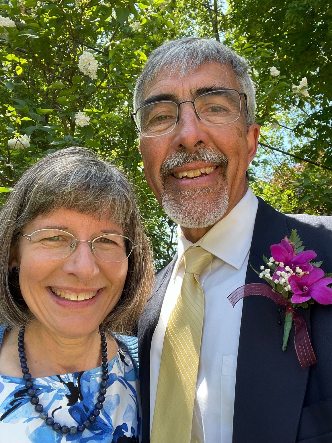 Pete Sehloff with his wife, Sarah. They are outside with blossoming trees in the background