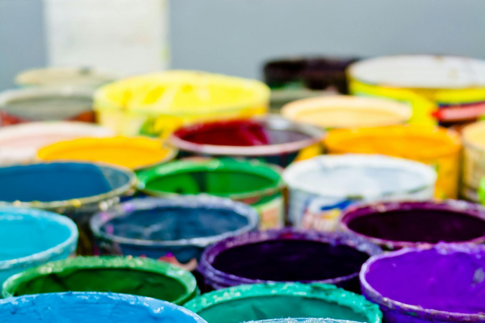 Many open paint cans of a variety of colors