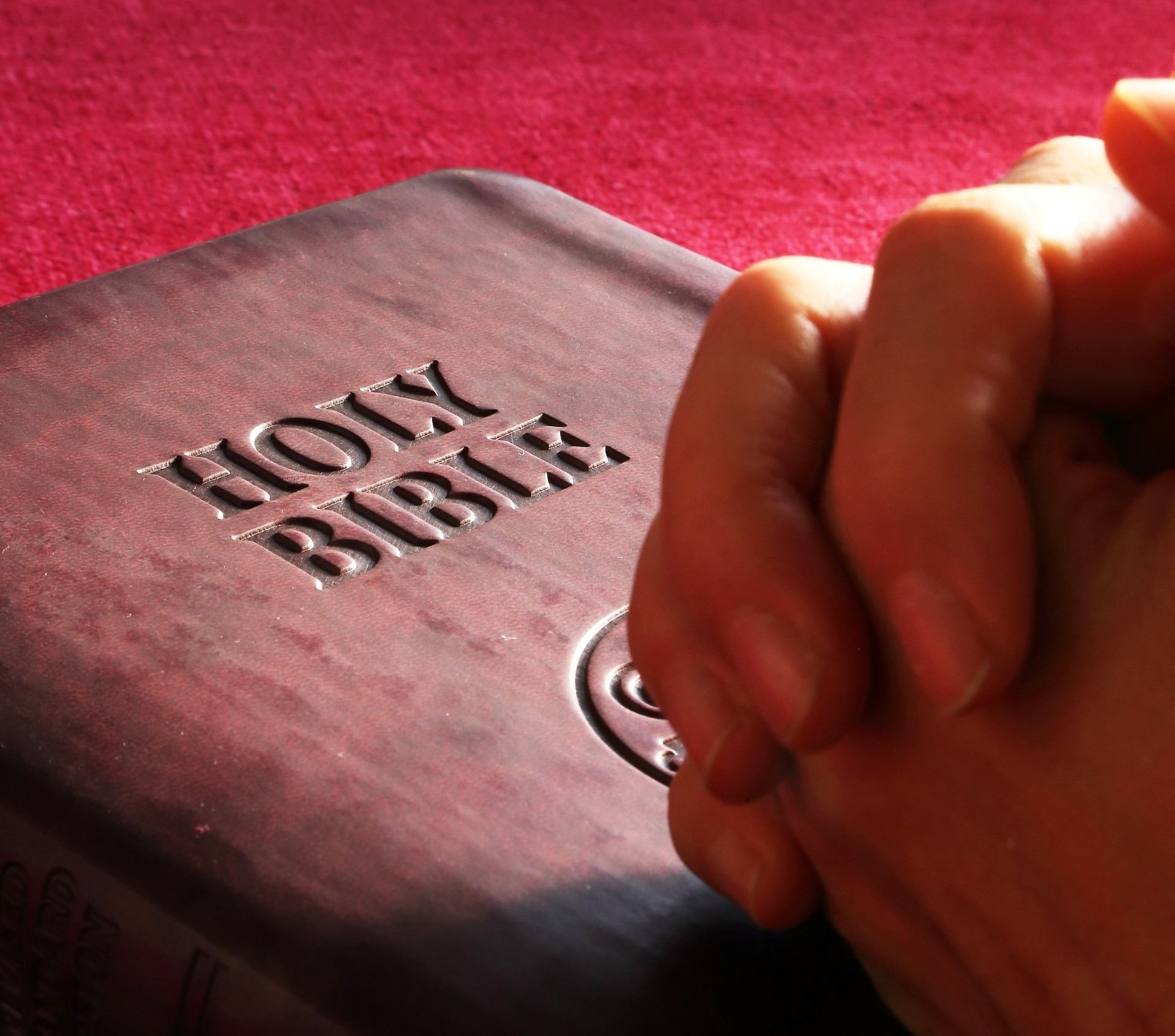 Folded hands on a Bible