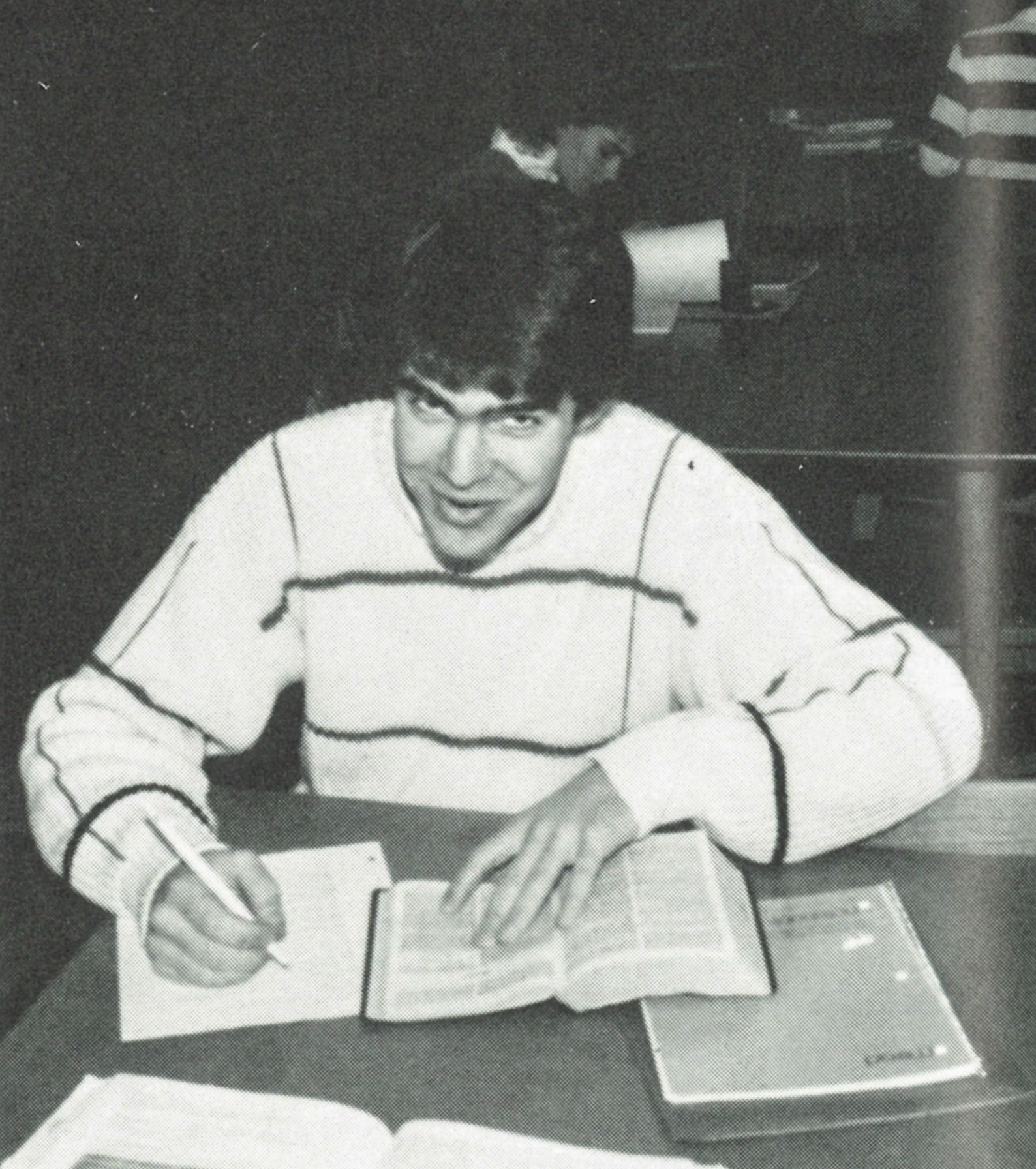 Male student at a table, with a notebook and open Bible
