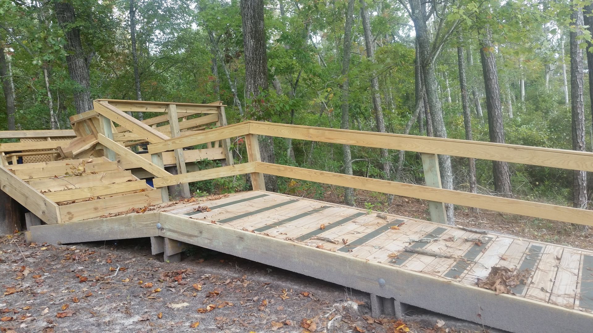 Wooden wheelchair ramp with railings in a wooded park setting