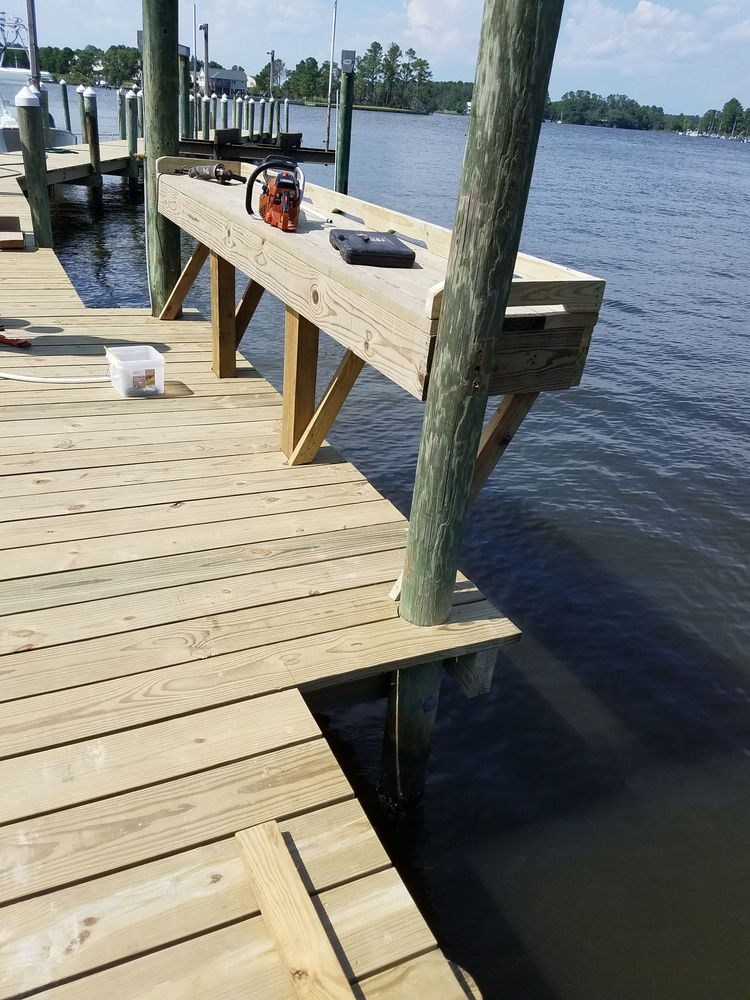 Wooden dock under construction beside a lake, with tools and supports on the walkway.