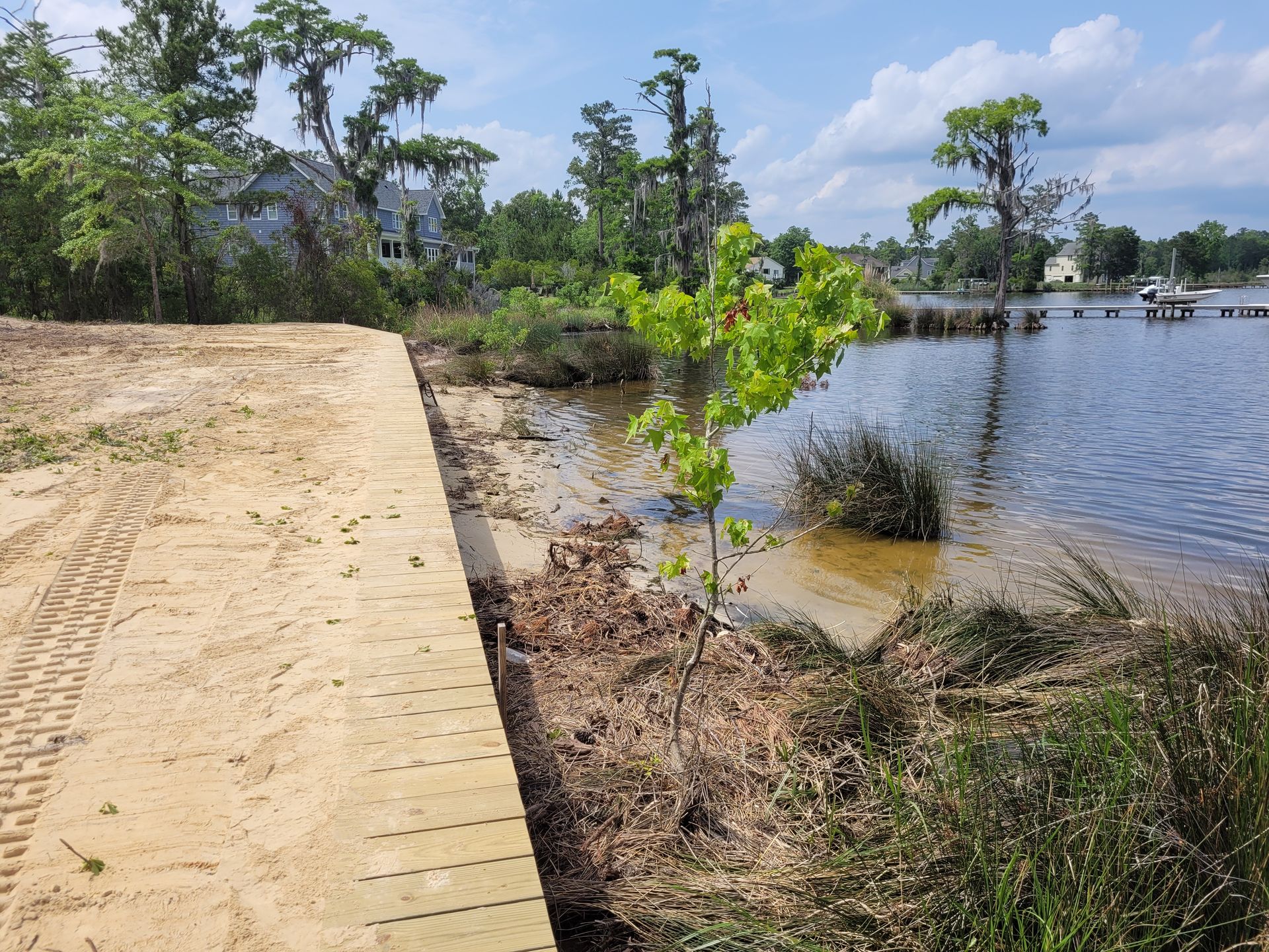 Brick path beside a calm lake with trees and blue sky on a sunny day