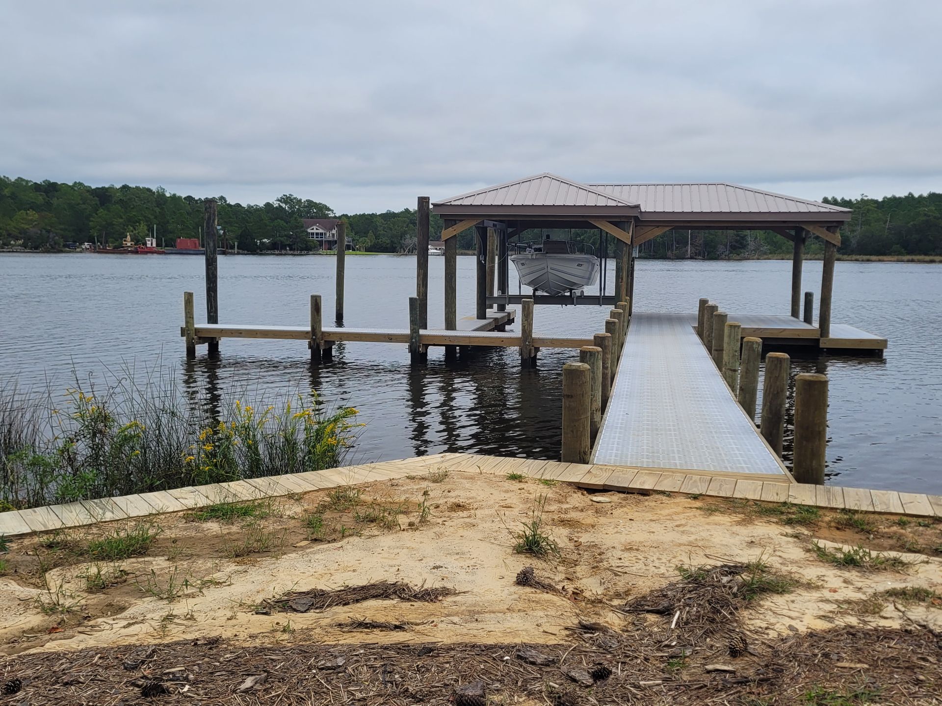 Wooden dock and covered gazebo extending into a calm lake under an overcast sky