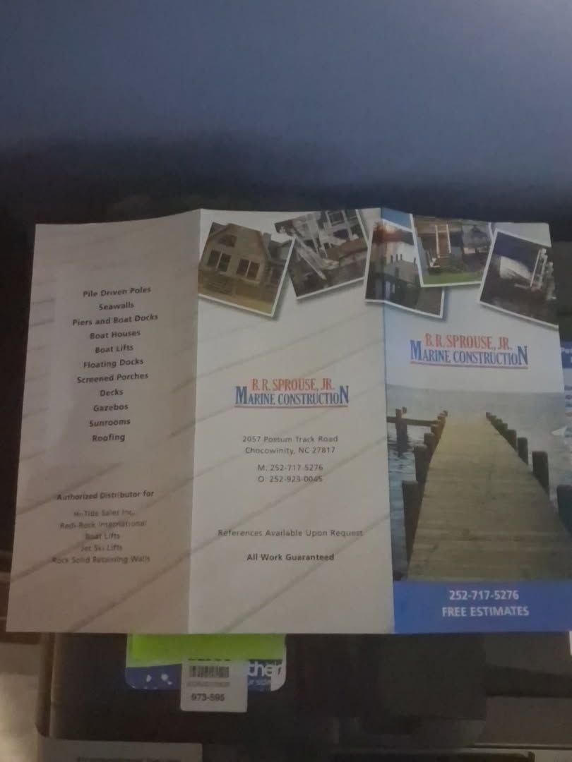 Tri-fold brochure with photos of a building, walkway, and floor plan on a dark surface