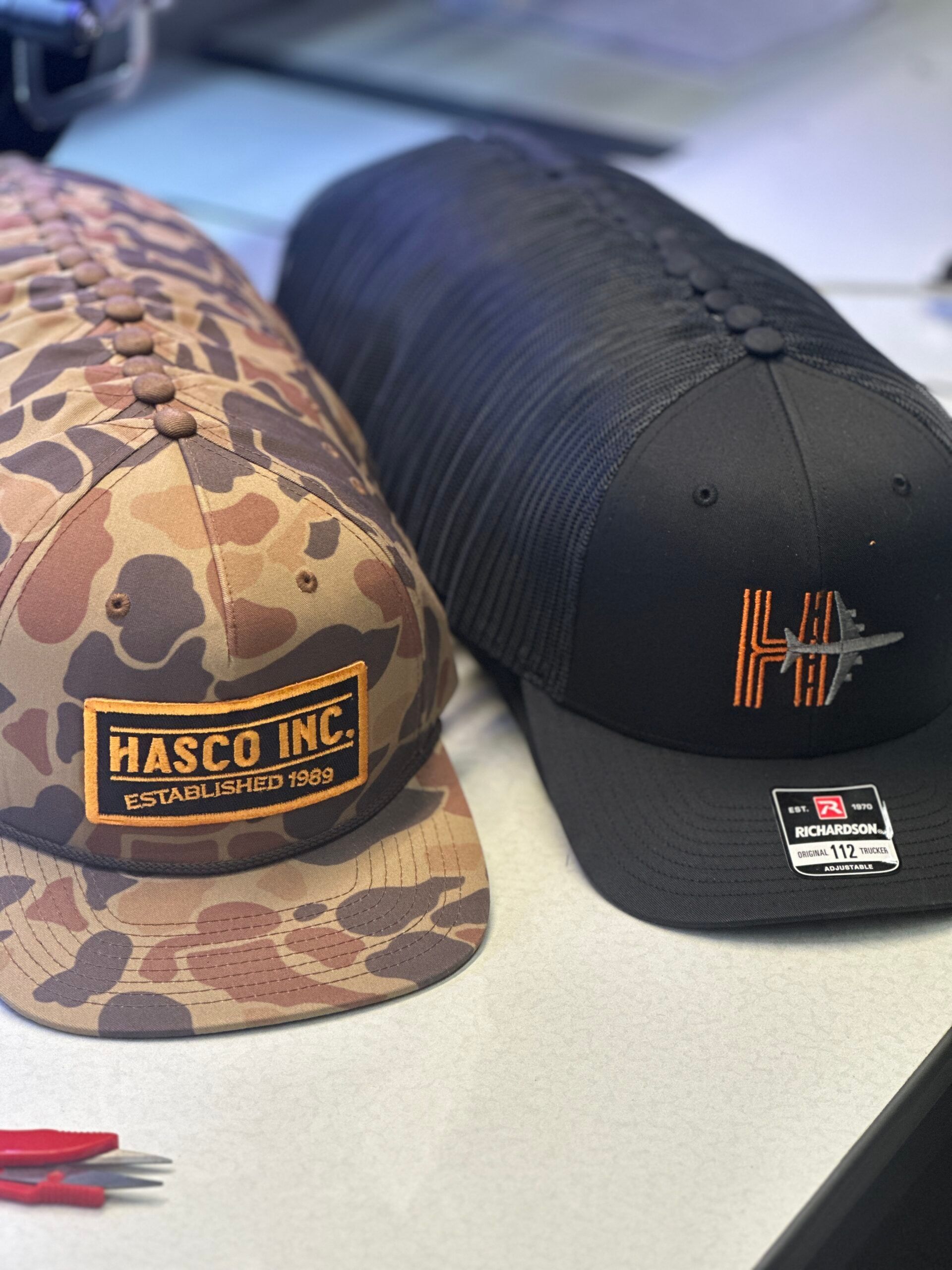 Two baseball caps: one camouflage with 
