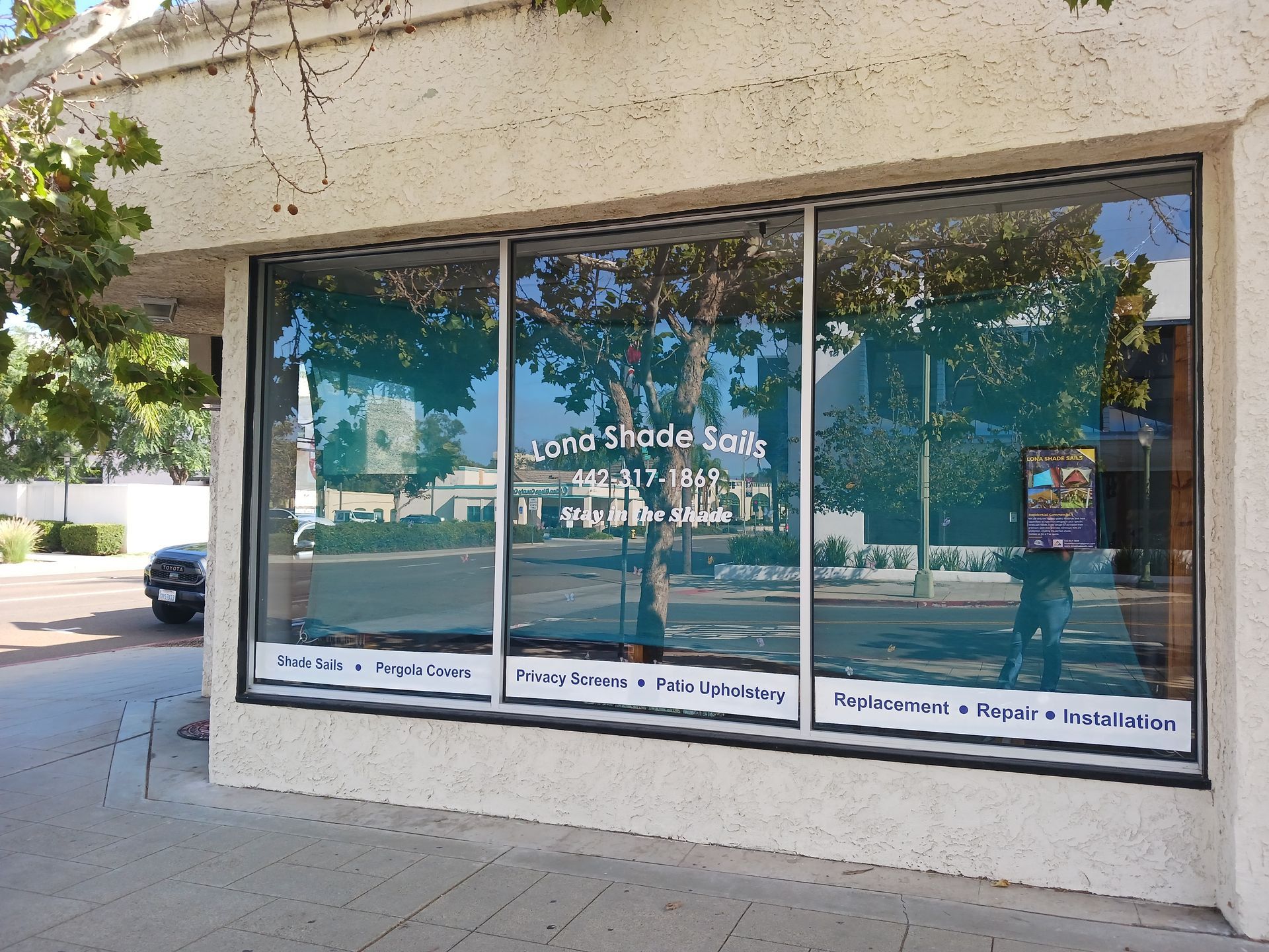 Storefront with large reflective windows and signage on a sunny street corner