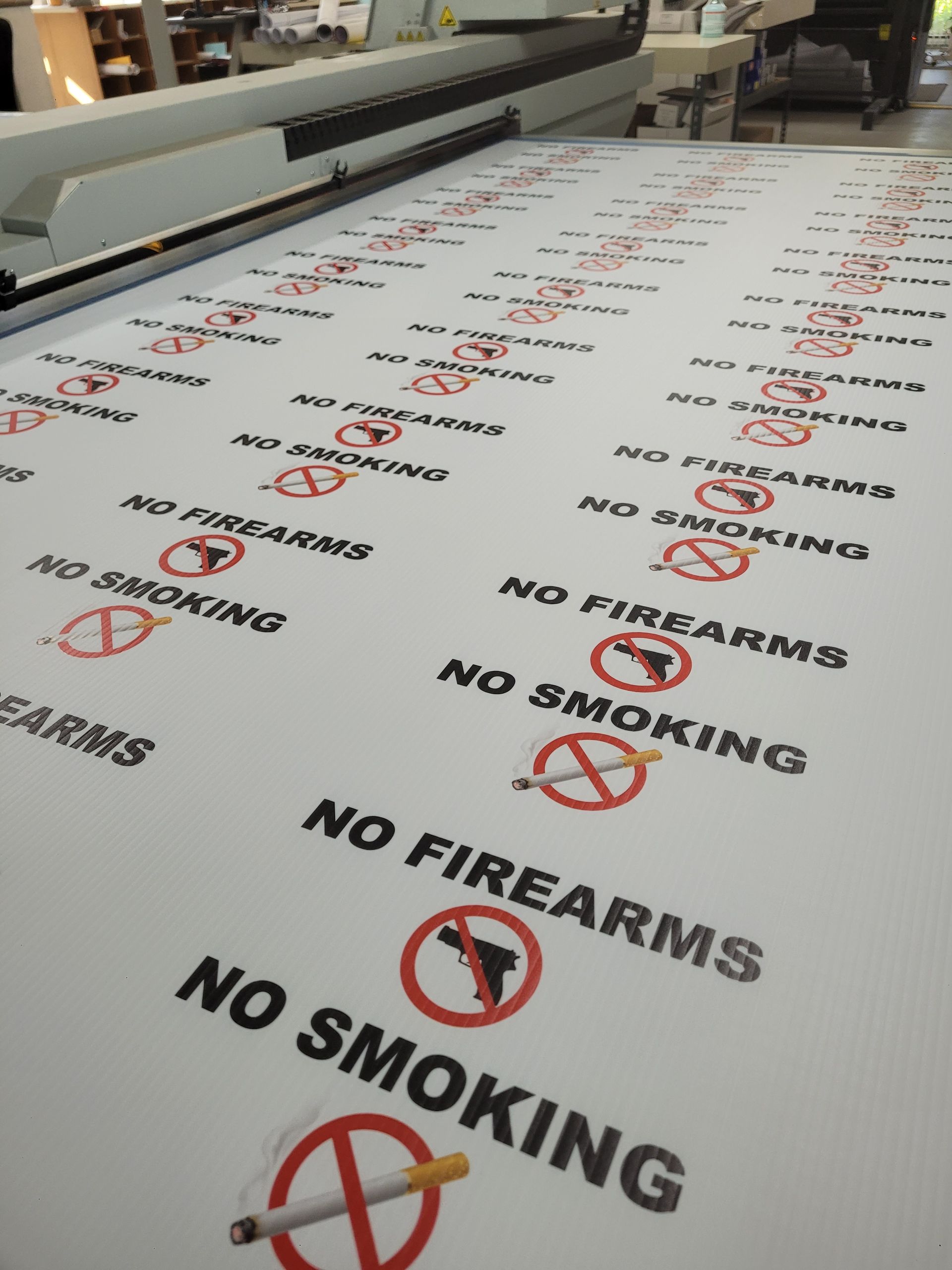 Printed sheets with repeated red “No Smoking” and “No Firearms” signs on a production line
